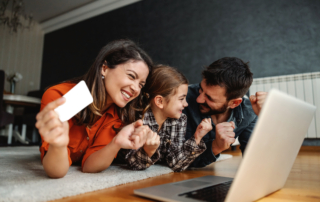 Happy family using laptop for online shopping. They are excited for purchase. Mom holding credit card.